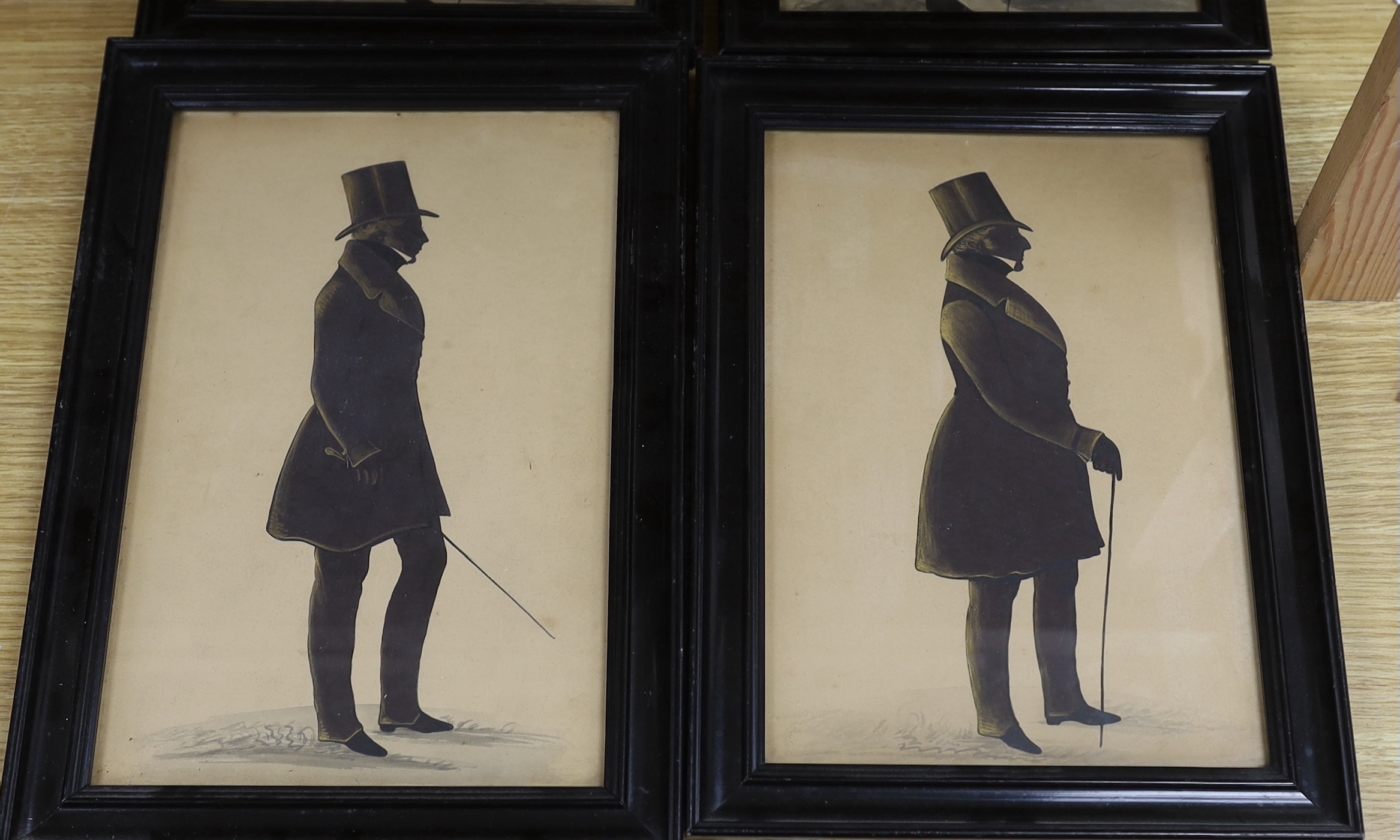 Victorian School, four cut and bronzed paper silhouettes, Full length profiles of gentlemen wearing frock coats and top hats, largest 28 x 18cm